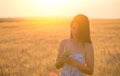 Beautiful woman with a wheat bouguet in wheat field at sunset