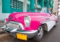 The beautiful woman at a wheel old American retro car (50th years of the last century), an iconic sight in the city, on the