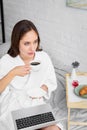 beautiful woman in white bathrobe with laptop drinking coffee Royalty Free Stock Photo