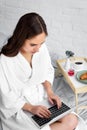 beautiful woman in white bathrobe using laptop during breakfast Royalty Free Stock Photo