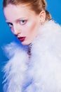 Beautiful woman in white cape of feathers. Fashion photo