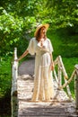beautiful woman in a white dress and hat stands on a birch bridge Royalty Free Stock Photo