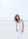 Beautiful woman in a white dress on the ocean coast. Happy girl on the beach, the wind fluttering hair. Royalty Free Stock Photo
