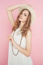 Beautiful woman in white dress posing on pink background in hat Royalty Free Stock Photo