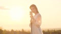 beautiful woman in white dress sings into retro microphone at dawn, sun shines in camera. Cheerful young lady singing