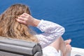 Beautiful woman in white dress sunglasses sitting on chair on white terrace of villa hotel resort looking at Sea View