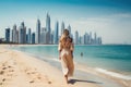 Beautiful woman in white dress walking on the beach with skyscrapers in Dubai, beautiful woman walking on the beach in Dubai. In