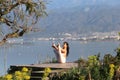 A beautiful woman in a white gymnastic jumpsuit performs yoga on the background of the mountains and the sea Royalty Free Stock Photo