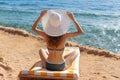 beautiful woman in white hat and bikini sitting on lounger near sea on beach in Egypt. Summer holiday concept travel Royalty Free Stock Photo