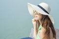 Beautiful woman in white hat is sitting on the hotel with the beach Royalty Free Stock Photo