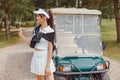 Beautiful woman in white outfit standing near golf cart Royalty Free Stock Photo