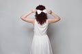 Beautiful woman with white silky bow hairpin in her red curly hair standing on white background