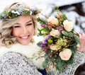 Attractive woman with white teeth and a perfect smile holds a bouquet of roses and fir branches. Happy sincere winter outdoor Royalty Free Stock Photo