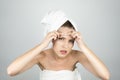 Beautiful woman in white towel on her head squeezing pimple on her forehead isolated white background