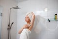 Beautiful woman in white towel shaving her armpits with razor in shower cabin. Depilatory procedure at bathroom