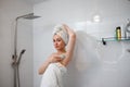 Beautiful woman in white towel shaving her armpits with razor in shower cabin. Depilatory procedure at bathroom