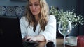 Beautiful woman in white working on a laptop in her kitchen Royalty Free Stock Photo