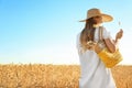 Beautiful woman with wicker bag in wheat field on sunny day Royalty Free Stock Photo