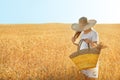 Beautiful woman with wicker bag in wheat field on sunny day Royalty Free Stock Photo