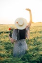 Beautiful woman with wildflowers enjoying sunset in barley field. Atmospheric tranquil moment, rustic slow life. Stylish female Royalty Free Stock Photo