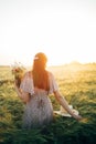 Beautiful woman with wildflowers enjoying sunset in barley field. Atmospheric tranquil moment, rustic slow life. Stylish female Royalty Free Stock Photo
