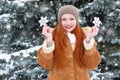 Beautiful woman on winter outdoor posing with big snowflake toys, holiday concept, snowy fir trees in forest, long red hair, weari