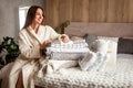 Beautiful woman in winter thick warm robe is sitting and neatly folding bed linens and bath towels