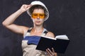 Beautiful woman worker builder in uniform with white helmet holds notebook. Portrait of cute young builder girl in work clothes. Royalty Free Stock Photo