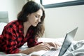 Beautiful woman working on a laptop with smiling and lying down on the bed at a condominium in the morning Royalty Free Stock Photo