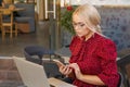 Beautiful woman works on laptop in coffee shop and using mobile phone in a red Royalty Free Stock Photo