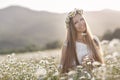 Beautiful woman in a wreath of real flowers, with a bouquet in a field of white daisies Royalty Free Stock Photo