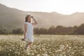 Beautiful woman in a wreath of real flowers, with a bouquet in a field of white daisies Royalty Free Stock Photo