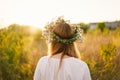 Beautiful woman in a wreath of wild flowers. Standing back in the flower field, hands to the side Royalty Free Stock Photo