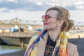 A beautiful WOMAN of 40-45 years old with glasses and a scarf on the background of urban multi-storey buildings. Royalty Free Stock Photo