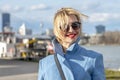 A beautiful WOMAN of 40-45 years old with glasses and a scarf on the background of urban multi-storey buildings. Royalty Free Stock Photo