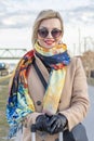 A beautiful WOMAN of 40-45 years old with glasses and a scarf on the background of urban multi-storey buildings. Royalty Free Stock Photo