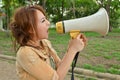 Beautiful woman yelling into megaphone in the park Royalty Free Stock Photo
