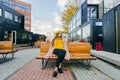 Beautiful woman in yellow beret sits on the street on the bench, depicts emotions. Summer time, yellow colors Royalty Free Stock Photo