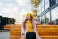 Beautiful woman in yellow beret sits on the street on the bench, depicts emotions. Summer time, yellow colors Royalty Free Stock Photo