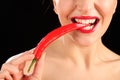 Beautiful womans mouth biting on red chili pepper