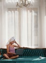 Beautiful women in bathrobes and towels in bedroom working on computer at home. Beautiful girl using laptop computer in Royalty Free Stock Photo