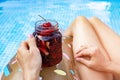 Beautiful women in the in blue swimming pool. A woman`s graceful hand holds a berry cocktail. Inflatable donut. Close-up Royalty Free Stock Photo