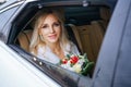 Beautiful woman bride with a bouquet of flowers and a man sitting in the car, looking out the window Royalty Free Stock Photo