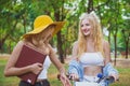 Two beautiful women in conversation while walking with bicycle at park Royalty Free Stock Photo