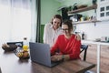 Beautiful woman lesbian couple talking and using laptop and smartphone at kitchen room, couple living together at home Royalty Free Stock Photo