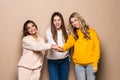 Beautiful three women friends standing with hands on top each other and smiling  on beige background Royalty Free Stock Photo