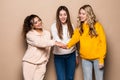 Beautiful three women friends standing with hands on top each other and smiling  on beige background Royalty Free Stock Photo