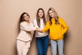 Beautiful three women friends standing with hands on top each other and smiling isolated on beige background Royalty Free Stock Photo