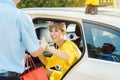 Woman getting out of taxi and the driver helping her