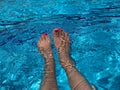 Beautiful women legs in blue water. Beautiful female feet relaxing by the swimming pool. Summer background for traveling Royalty Free Stock Photo